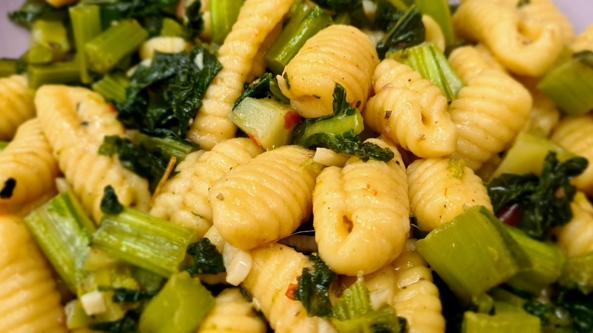 Cavatelli con Cime di Rapa in Nahaufnahme, man sieht die Pasta mit den Stücken vom Stängelkohl, Knoblauch, Chiliflocken und Gewürzen