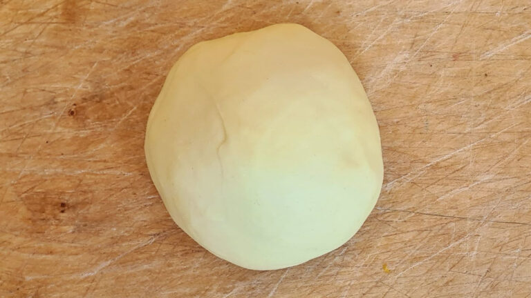 Eine Kugel Pastateig aus Hartweizen auf einem Brett