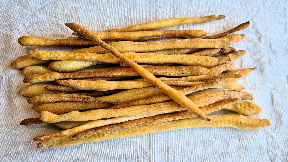 Grissini auf einem weißen Tuch, ein Grissino liegt quer über den anderen
