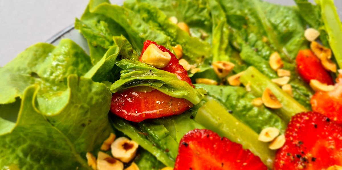 Der bunte Keulensalat in Großaufnahme, rote Erdbeeren, grüne Keule, braune Haselnüsse