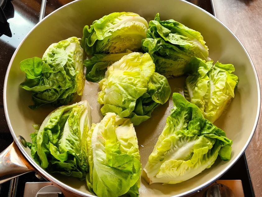 Angebratener Salat: Man sieht die frischen grünen Salatherzen halbiert oder geviertelt in der Pfanne.