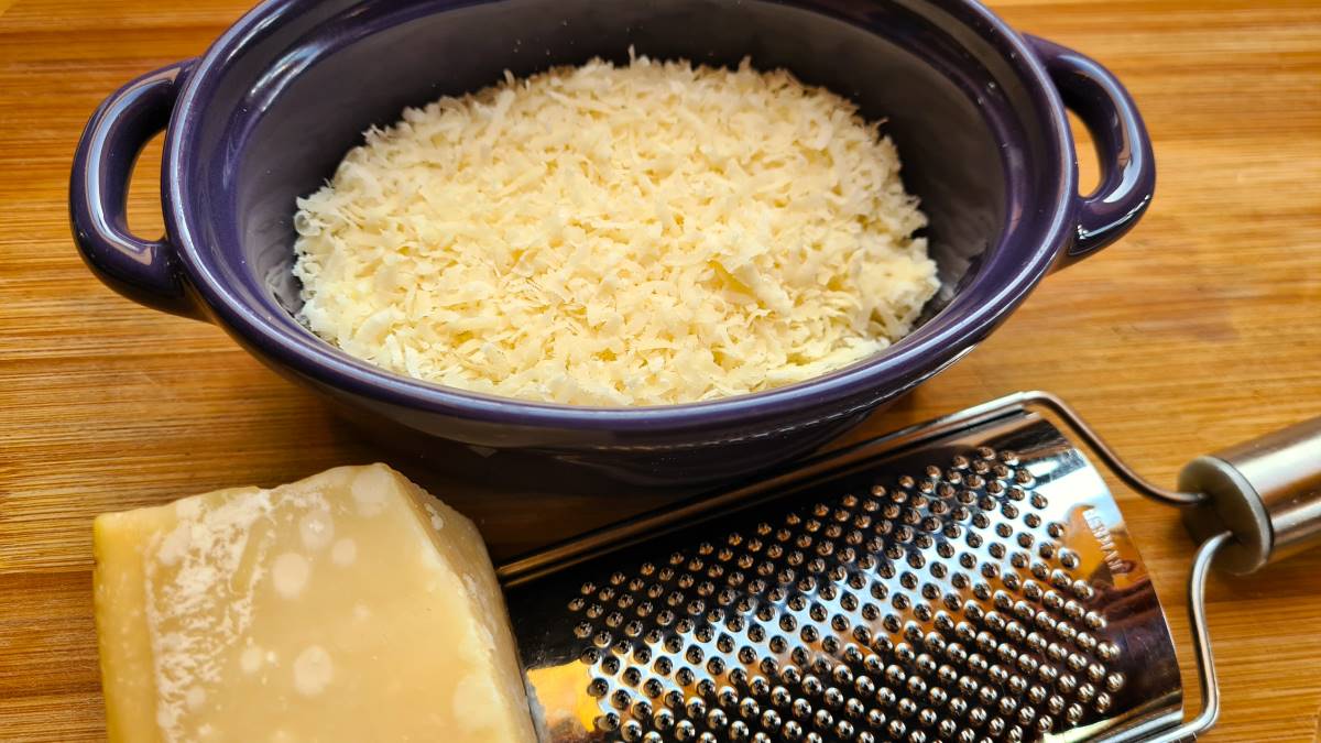 Parmesan als natürlicher Geschmacksverstärker: Hier geriebener Parmesan und eine Reibe