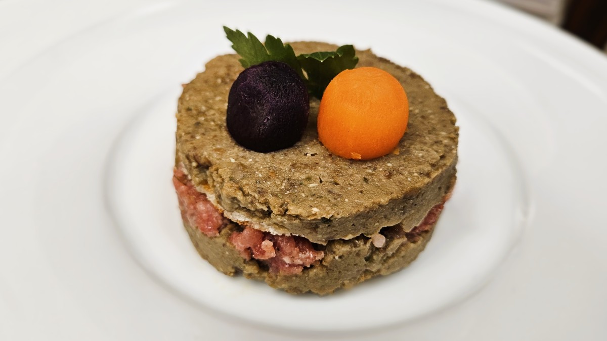 Musetto Linsen Millefoglie in runden Scheiben angerichtet auf einem weißen Teller mit einer violetten und einer orangen Karottenkugel obendrauf