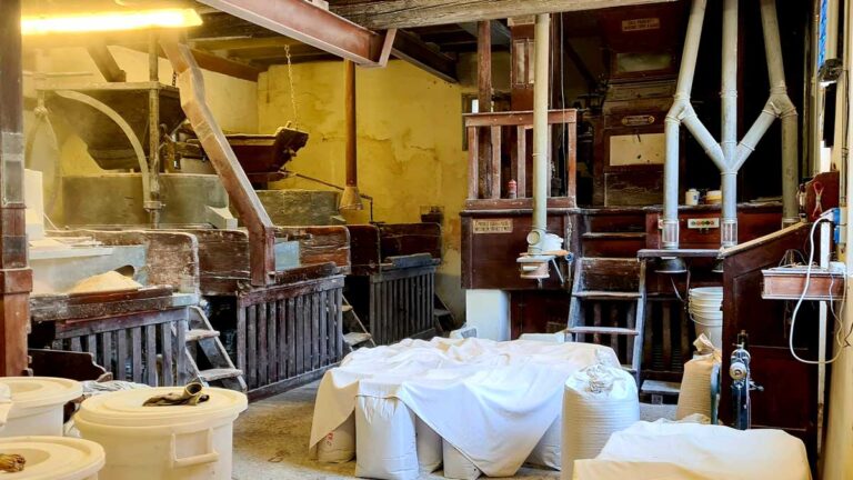 Das Innere der Mühle Zoratto, Mühlsteine, Bottiche, Säcke mit Getreide und Mehl