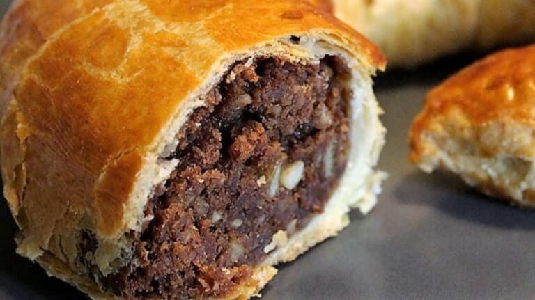 Ein angeschnittener Kuchen, eine wurstartige Form, die Fülle ummantelt mit einer Art Strudelteig