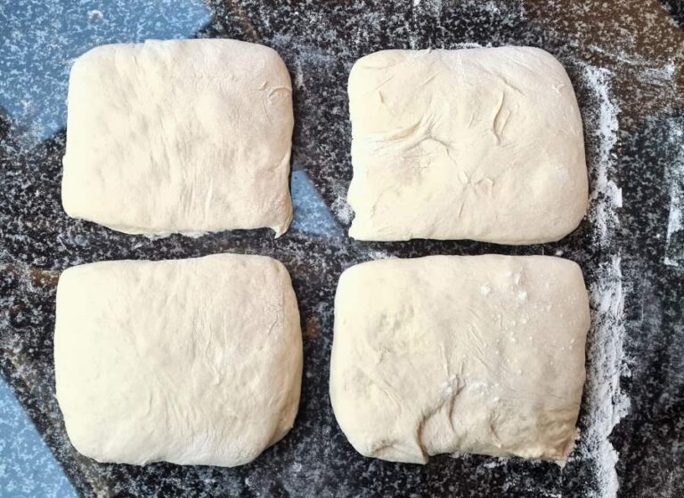 Man sieht den rohen reifen Teig in vier ungefähr gleich große Quadrate geteilt