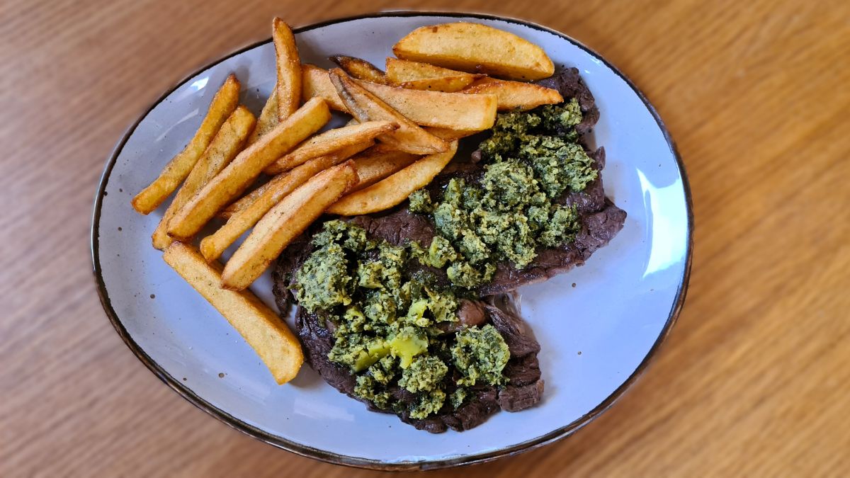 Auf einem Teller ein großes Entrecote mit der Butter "Café de Paris", daneben hausgemachte Pommes frites