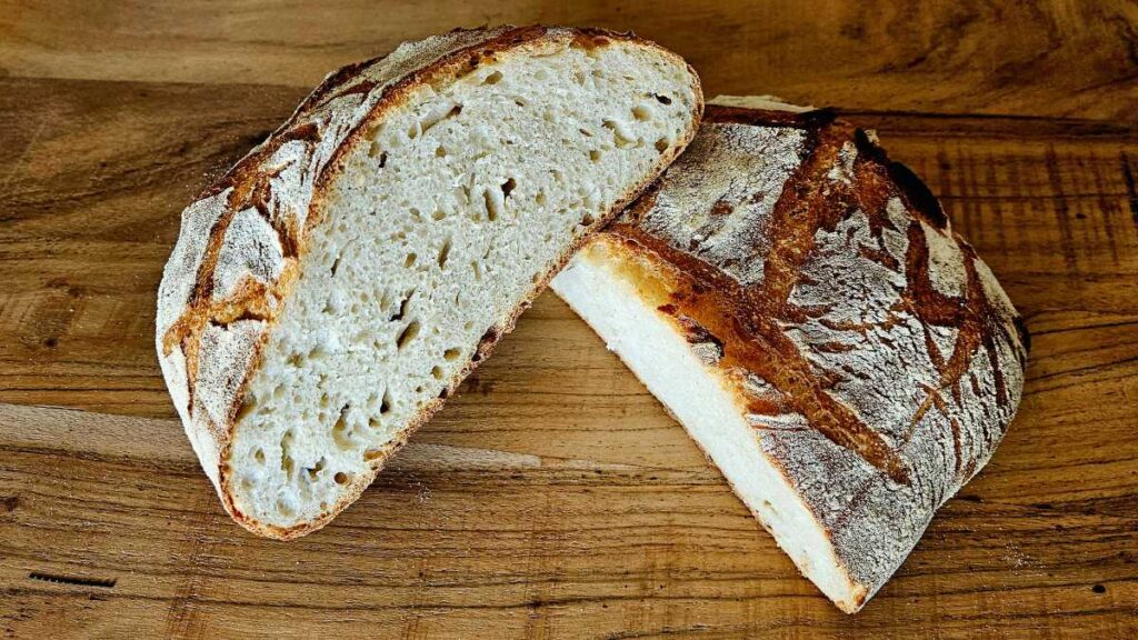 Man sieht den angeschnittenen Laib Brot nach der Lievito-Madre-Brotformel: helle Krume, leicht unregelmäßige Porung, kräftige Kruste
