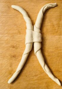Ein rohes Pane Ferrarese: zu sehen sind die zwei gerollten Teigstücke, die mit den kleinen Enden der Teigplatten verbunden sind