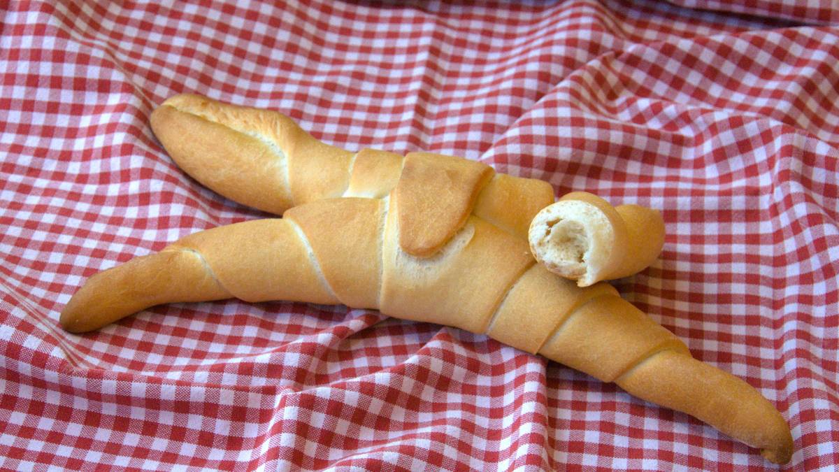 Auf einem rot-weiß-karierten Tuch liegt ein Pane Ferrarese, einer von den vier Zipfeln ist abgebrochen, so dass man die weiche Krume siehen kann.