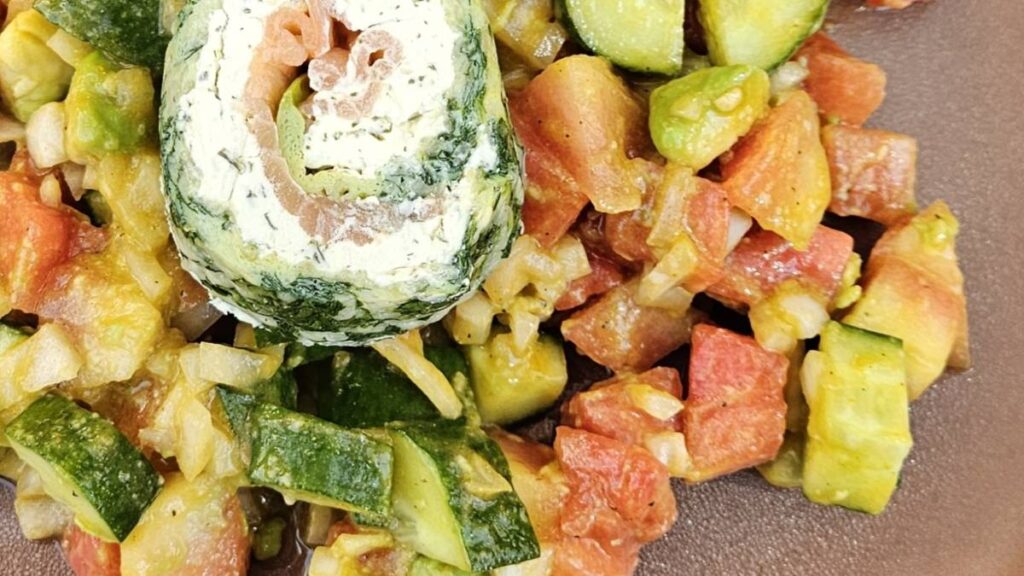 Das Bild zeigt einen vergrößerten Ausschnitt des Wassermelonensalat mit Kurkumadressing; zu sehen sind die Zutaten wie Wassermelone, Gurke und Avocado mit dem leicht cremigen gelben Dressing.